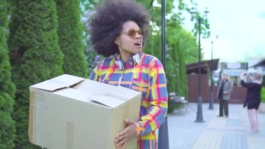 Bir afro saç modeli ile portre Afrikalı Amerikan kadın o elinde bir kutu ile sokakta yürüyor ve damla