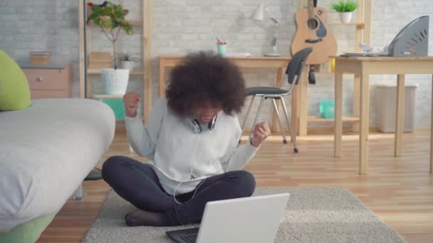 美丽的非洲裔美国妇女与一个fro发型坐在地板上与笔记本电脑了解的胜利 — 图库视频影像
