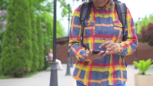 Turista mujer africana con un peinado afro utiliza un teléfono inteligente — Vídeo de stock