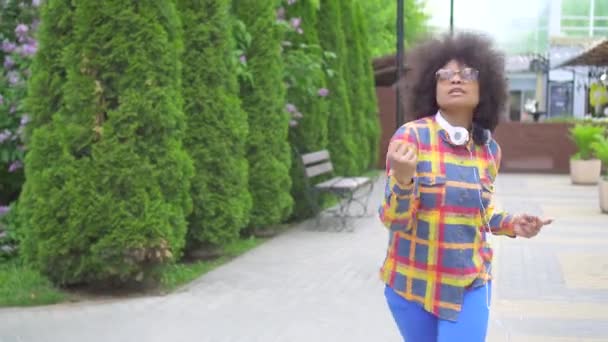 Positiva allegra ragazza afroamericana che cammina e balla per strada, contro il paesaggio urbano — Video Stock