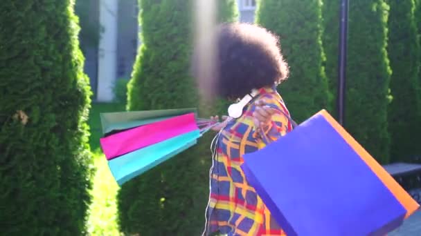 Alegre afroamericana mujer con un afro peinado con paquetes después de ir de compras lento mo — Vídeo de stock