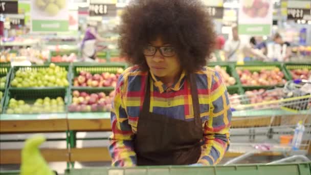 Σούπερ μάρκετ υπάλληλος αφρικανική Αμερικάνικη γυναίκα με ένα αφροάφρο χτένισμα ταξινομεί τα φρούτα — Αρχείο Βίντεο