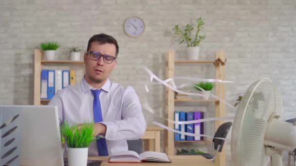 Młody człowiek pracuje na laptopie w biurze siedzi przed wentylatorem powoli mo — Wideo stockowe