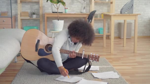 Mulher africana americana com um penteado afro sentado no chão com uma guitarra experimentando uma crise criativa — Vídeo de Stock