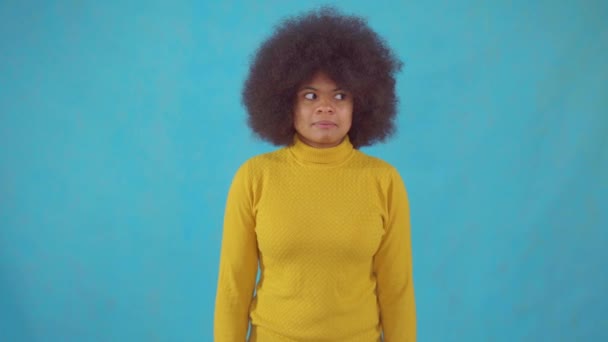 Mujer africana confusa con un peinado afro en una chaqueta amarilla — Vídeo de stock
