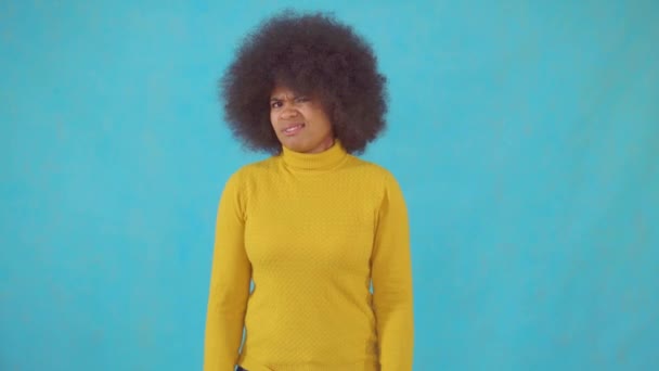 Mujer africana con un peinado afro en una chaqueta amarilla muestra negación — Vídeo de stock