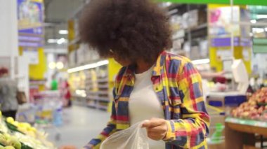 Bir afro saç modeli ile güzel afro-amerikan kadın süpermarkette meyve satın alır