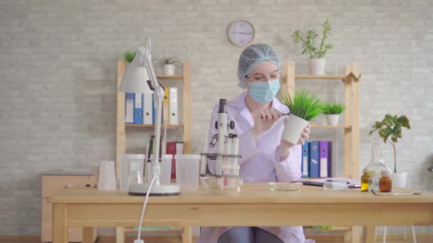 Vrouw laboratorium assistent voert een studie van de plant met een microscoop in een modern laboratorium — Stockvideo