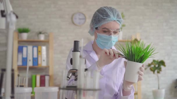 Портрет женщины-лаборанта проводит исследование растения под микроскопом — стоковое видео