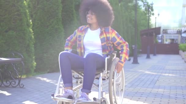 Retrato de uma jovem afro-americana sorrindo positiva desativada em uma cadeira de rodas na rua — Vídeo de Stock