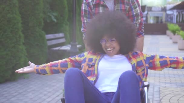 Olumlu gülümseyen genç Afro-Amerikan kadın tekerlekli sandalyede engelli portresi ve arkadaşı sevinir ve ellerini yakın çekim yükseltir — Stok video