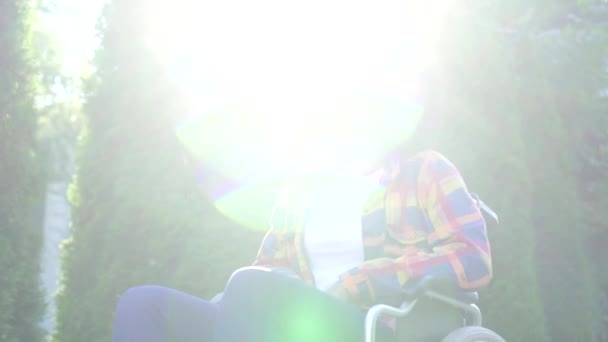 在阳光明媚的日子里，一位面带微笑的年轻非洲裔美国妇女坐在轮椅上看着相机 — 图库视频影像