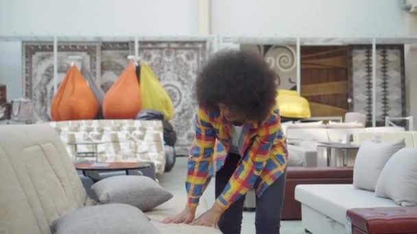 Mujer afroamericana con un peinado afro elige un sofá en una tienda de muebles — Vídeo de stock