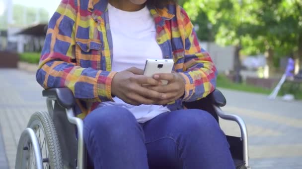 Manos negras mujeres discapacitadas en una silla de ruedas de cerca usando un teléfono inteligente — Vídeo de stock