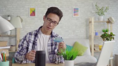 elinde banka kartı olan bir gömlek genç asyalı adam bir ses asistanı kullanır
