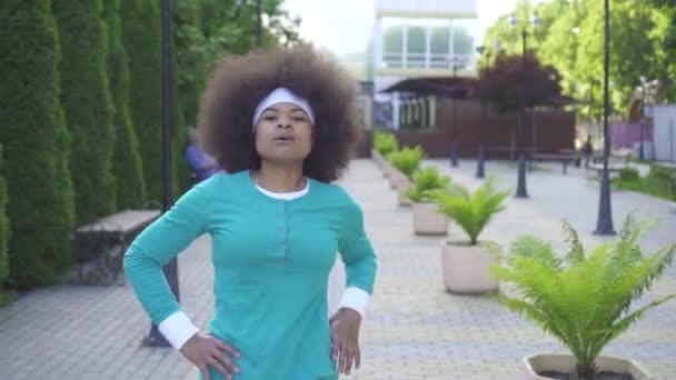 Портрет посміхаючись спортивна Африканська жінка з афро зачіска в сонячному парку — стокове відео