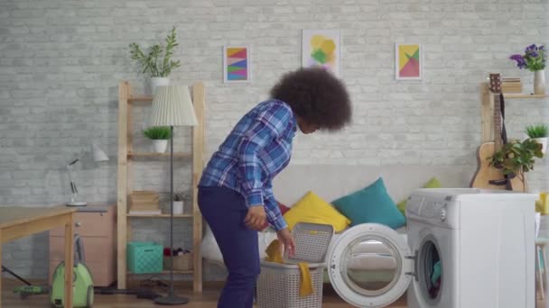 Afro-americana dona de casa na camisa fazendo lição de casa, tirando roupas lavadas em casa — Vídeo de Stock