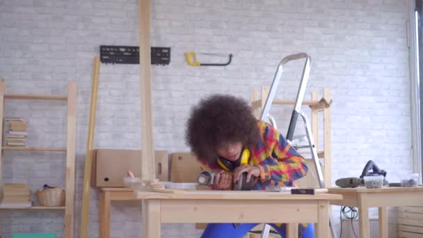 African woman with an afro hairstyle works on wood in the workshop — Stock Video