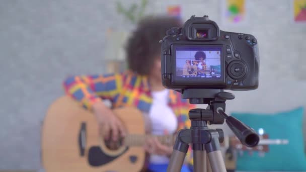 Blogger africana con un peinado afro con una guitarra la vista a través de la pantalla de la cámara — Vídeo de stock