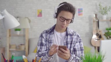 elinde bir akıllı telefon ile genç asyalı adam kulaklık ile müzik dinlerken