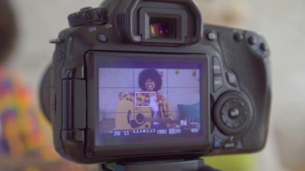 Afrikaanse vrouw Blogger met een Afro kapsel met een gitaar het uitzicht door het camerascherm close-up — Stockvideo