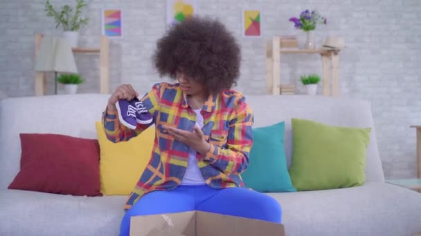 Verrast en boos Afro-Amerikaanse vrouw met een Afro kapsel pakt het pakket, verkeerde grootte — Stockvideo