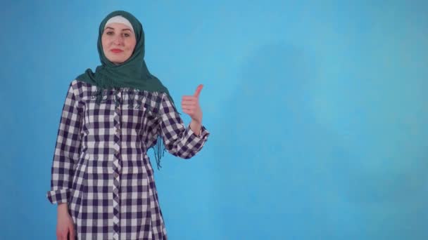 Young Muslim woman showing thumbs up on a blue background — Stock Video