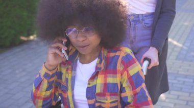 telefonda konuşurken tekerlekli sandalyede engelli olumlu gülümseyen genç Afro-Amerikan kadın portresi