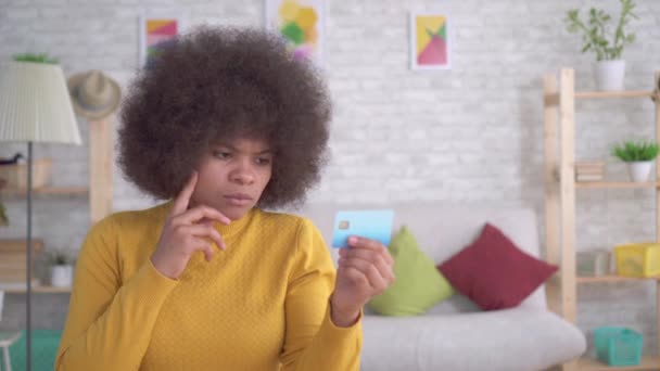 Retrato mujer afroamericana reflexivo y serio mirando la tarjeta bancaria en sus manos — Vídeo de stock