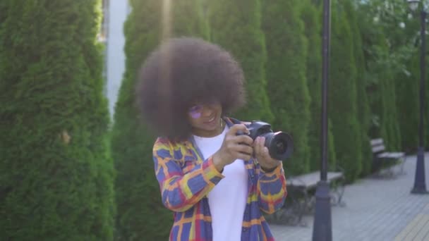 Πορτραίτο αφρικανική γυναίκα με ένα μαύρος/η χτένισμα φωτογράφος με μια κάμερα στο αστικό τοπίο — Αρχείο Βίντεο