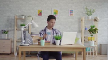 bir gömlek genç asyalı adam bir dizüstü bilgisayarda bir Banka kartı ile veri girer