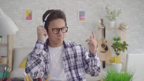 Портрет молодого азиата, слушающего энергичную музыку в наушниках — стоковое видео