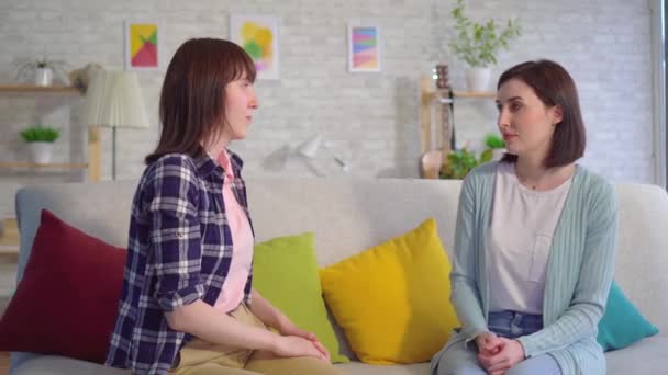 Zwei schöne gehörlose junge Frauen im Gespräch mit Gebärdensprache im Wohnzimmer aus nächster Nähe — Stockvideo