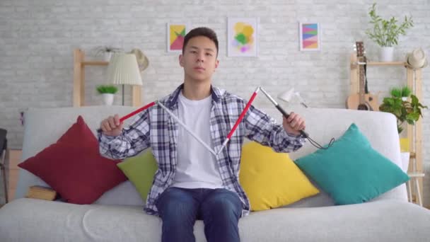Blind asiatisk ung man sitter på soffan i vardagsrummet — Stockvideo