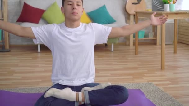 Genç asyalı adam yakın mat üzerinde oturan yoga yapıyor — Stok video