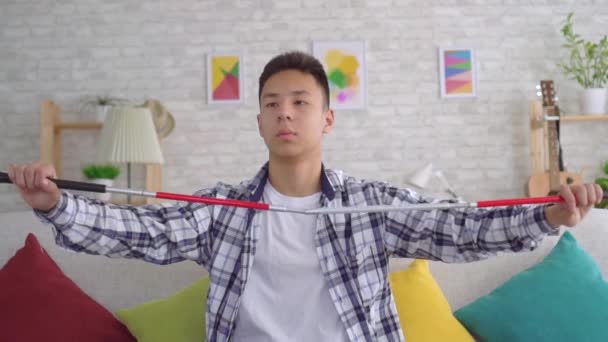 Vak ázsiai fiatalember ül a kanapén a nappaliban lassú Mo — Stock videók