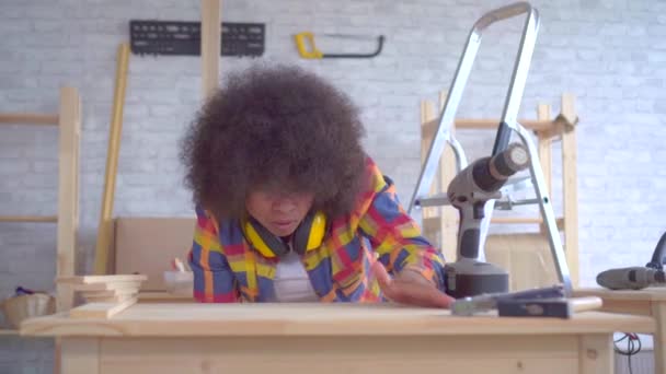 Afrikanerin mit Afro-Frisur arbeitet in der Werkstatt an Holz — Stockvideo