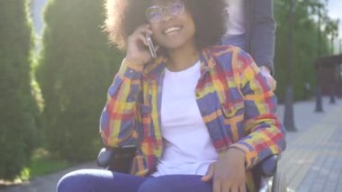 parkta telefonda konuşurken bir tekerlekli sandalye olumlu engelli bir afro saç modeli ile Afrikalı kadın