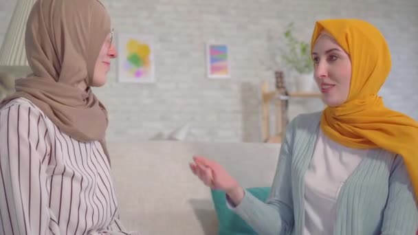 Portrét dvě nádherné hluché mladé muslimské ženy v hijabs mluvení s Podepisovatelským jazykem v obývacím pokoji zavřít — Stock video