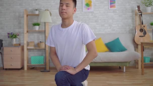 Ung asiatisk man gör en uppvärmning på mattan — Stockvideo