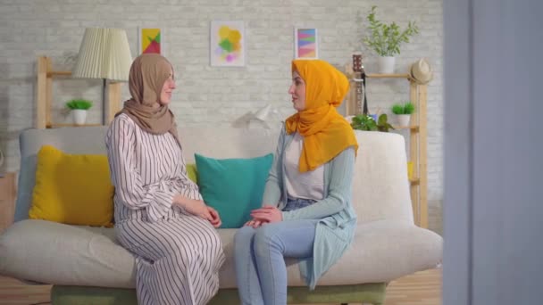 Portret twee mooie dove jonge Moslimvrouwen in hijabs praten met gebarentaal in de woonkamer — Stockvideo