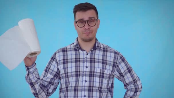 Portret positieve jonge man staande op een blauwe achtergrond en het houden van papieren handdoeken — Stockvideo