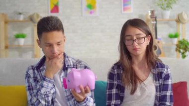Elinde kumbara ile Düşünceli genç sian çift kanepede oturan
