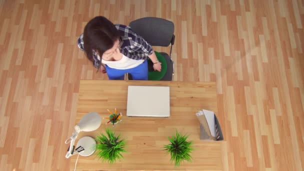 Wanita muda yang duduk di atas bantal hijau ortopedi dari wasir yang bekerja di laptop, pandangan atas — Stok Video
