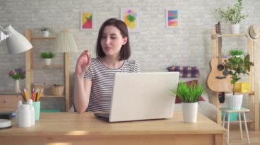 Bir dizüstü bilgisayarda internette bilgi arayan ve işitme cihazı tutan genç kadın