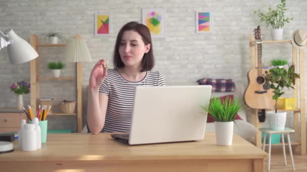 Jeune femme à la recherche d'informations sur Internet dans un ordinateur portable et tenant un appareil auditif — Video