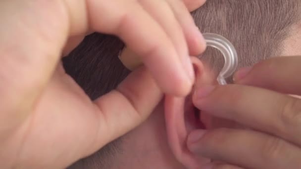 Мужчина вставляет слуховой аппарат ей в ухо. — стоковое видео