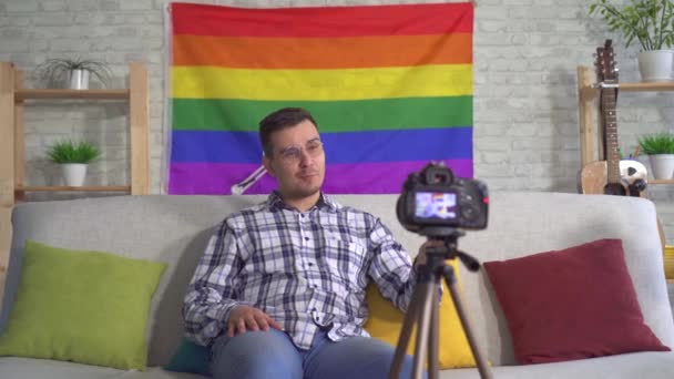 Retrato homem blogueiro meia-idade na camisa no fundo da bandeira do LGBT registros de vídeo — Vídeo de Stock