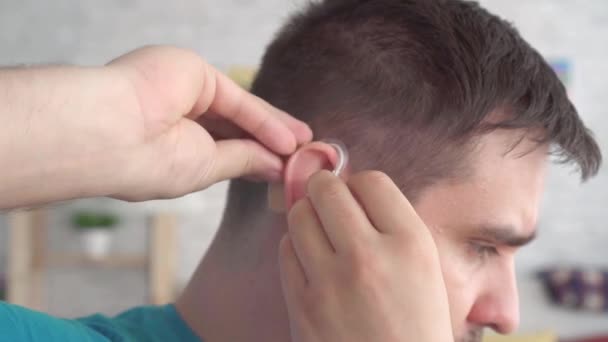 Man inserts a hearing aid into her ear — Stock Video