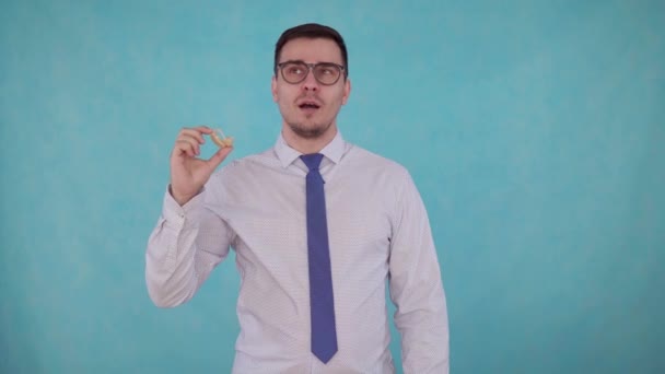 Man removes the hearing aid from his ear and hears on blue background — Stock Video